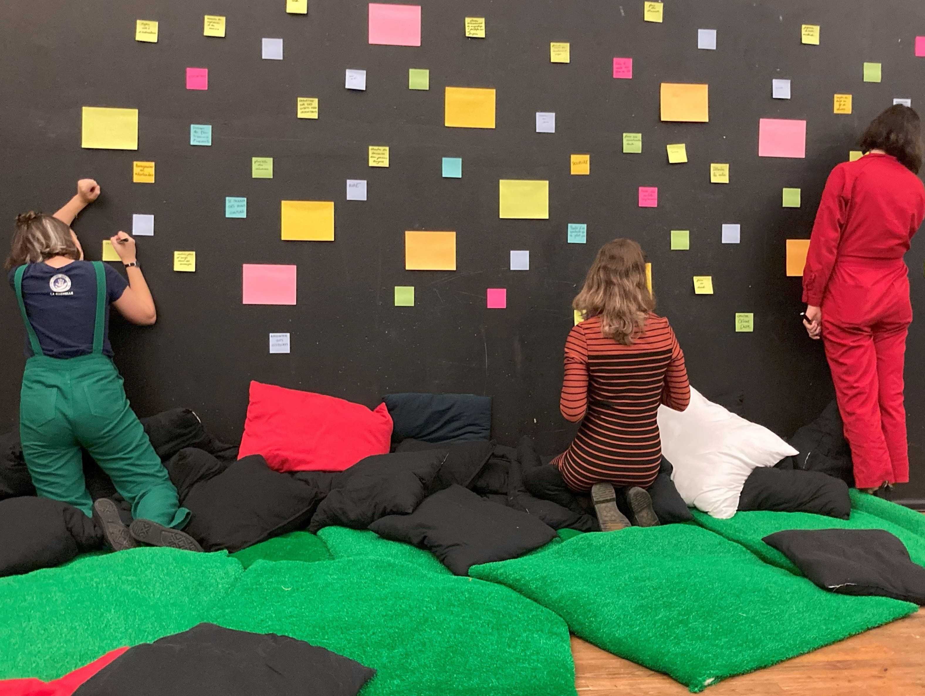 Des participantes d'un workshop qui écrivent sur un mur de post-it (version vignette)